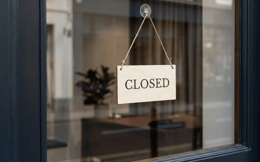A simple closed sign hanging in a window.