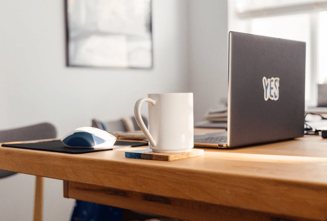 A calm home office desk with a laptop and notebook representing financial rules.